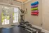 Bright home gym with an elliptical machine and colorful yoga mats, offering a refreshing workout space with a garden view.