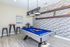Chic game room featuring a modern pool table, artistic decor, and vibrant lighting on stylish laminate flooring.