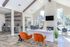 Bright and inviting office space with modern decor, featuring plush orange chairs, elegant marble surfaces, and large windows overlooking a lush garden.