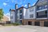 Modern apartment complex with charming architecture featuring brick accents and spacious balconies, set against a bright blue sky.