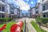 Modern apartment complex courtyard with vibrant play area, featuring stylish stone and siding fa&ccedil;ade under a bright blue sky.