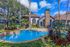 Inviting residential area featuring a sparkling pool surrounded by lush landscaping and charming architecture.