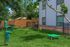 Charming outdoor area featuring a pet-friendly play zone with agility equipment, lush grass, and beautiful trees.