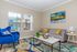 Contemporary living room with elegant design, featuring a plush blue armchair, comfortable gray couch with colorful cushions, and vibrant abstract artwork.