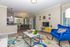 Chic living room with vibrant blue armchair, modern decor, open dining area, and elegant lighting.
