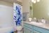 Bright and modern bathroom with elegant blue accents, featuring a granite countertop, stylish vanity, and a vibrant shower curtain.
