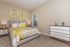 Bright and inviting bedroom featuring a stylish bed with yellow floral bedding, modern art, and elegant decor.