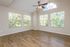 Bright and spacious room with elegant wood flooring, highlighted by large windows and vaulted ceiling with a stylish fan.