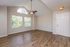 Bright living area with high ceilings, elegant wood floors, and large arched window for natural light.