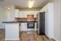 Modern kitchen with sleek black countertops, stainless steel appliances, and stylish white cabinetry on elegant wood flooring.
