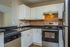 Charming contemporary kitchen featuring sleek stainless steel appliances, elegant black countertops, and crisp white cabinetry for a modern touch.