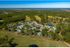 Serene aerial view of a lush green apartment complex nestled amid expansive forests and scenic golf courses, offering tranquil living surrounded by nature.