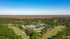 Breathtaking aerial view of a serene residential community nestled among lush green trees and expansive open fields.