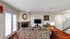 Inviting living room featuring elegant patterned sofas, a classic brick fireplace, and a stylish clock, complemented by rich wood flooring and natural light through double doors.