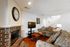 Charming living room with a cozy brick fireplace, plush sofas, and a modern flat-screen TV, enhanced by warm hardwood floors and elegant decor.