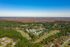 Breathtaking aerial view of a serene residential area surrounded by lush greenery and vast open landscapes, showcasing peaceful living in harmony with nature.