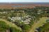 Aerial view of charming apartment complex nestled in lush greenery, featuring scenic landscapes, winding pathways, and serene water bodies for tranquil living.