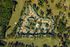 Aerial view of an expansive residential complex surrounded by lush greenery, featuring a central pool and recreational area.