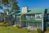 Charming two-story apartment building with green roofs, private balconies, and scenic views of lush surroundings.