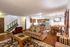 Cozy open-concept living room with striped furniture, modern kitchen with stainless steel appliances, and inviting dining area.