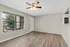 Bright and airy living room featuring sleek wood flooring, large window with blinds, a modern ceiling fan, and a cozy neutral palette.