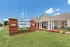 Charming entrance of The Heights on Oak, featuring a well-maintained lawn, blooming flowers, and inviting architectural design under a bright blue sky.