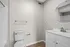 Bright and modern bathroom with elegant fixtures, featuring a sleek vanity, large mirror, and pristine white walls for a refreshing ambiance.