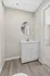 Chic bathroom nook featuring a stylish white vanity with a modern round mirror, complemented by sleek wood flooring.