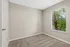 Bright and cozy empty room with plush carpet and a large window showcasing lush green views, perfect for personalization.