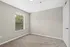 Bright and inviting room with neutral walls, plush carpet, and large window featuring natural light and serene views.