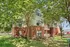 Inviting apartment building surrounded by lush green trees, featuring a charming brick and siding exterior with ample natural light and a cozy balcony.