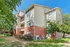 Attractive apartment complex with modern brick and siding facade, surrounded by lush greenery, under a clear blue sky.