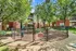 Charming apartment complex with a fenced dog park surrounded by greenery, perfect for pet lovers seeking a relaxing, nature-rich environment.