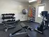 Modern apartment gym featuring state-of-the-art fitness equipment, including weights, exercise bike, and workout benches in a bright and inviting space.