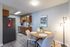 Inviting kitchen and dining area featuring a sleek stainless steel fridge, wooden cabinets, and a cozy round dining table with four chic chairs, perfect for intimate meals.