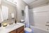 Elegant bathroom featuring sleek fixtures, modern white tiles, a cozy tub, and stylish decor with a hint of greenery.