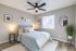 Elegant bedroom featuring a plush bed, modern ceiling fan, stylish decor, natural light from a large window, and warm ambient lighting.