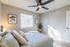 Inviting bedroom with modern design, featuring cozy bedding, elegant wall art, and a sleek ceiling fan.