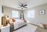 Bright and airy bedroom with modern decor, featuring large windows, a cozy bed, and stylish ceiling fan.