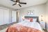 Inviting bedroom with modern decor, featuring a cozy bed, stylish lamps, and a ceiling fan, creating a perfect retreat.