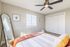 Bright and inviting bedroom with soft natural light, featuring a stylish ceiling fan, wall art, and a large full-length mirror.