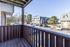 Charming second-floor view from a cozy apartment balcony overlooking a serene parking area and stylish buildings surrounded by lush trees.