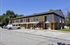 Charming two-story apartment building with a classic design, featuring balconies and ample parking space surrounded by lush greenery.