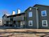 Charming two-story apartment building with private balconies and modern exterior design, set against a clear blue sky.