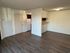 Bright apartment interior showcasing sleek wood flooring, open kitchen area, and inviting living space with ample natural light.