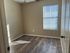 Bright bedroom featuring elegant wood flooring and a sunlit window with blinds, creating a cozy atmosphere.