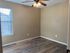 Cozy apartment bedroom with elegant wood flooring and ample natural light through large window.