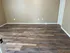 Spacious room with elegant, rich wood laminate flooring and neutral wall tones, perfect for personalized decor.
