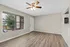 Inviting living room with elegant wood flooring, large window for natural light, and ceiling fan, creating a comfortable and airy space.