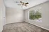 Bright and airy room with plush carpet, elegant ceiling fan, and large window offering a scenic view.